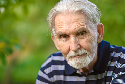 Elderly man with white beard and wearing blue striped shirt