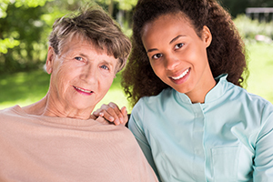 Elderly woman with short hair sitting outside with CNA wearing teal scrubs